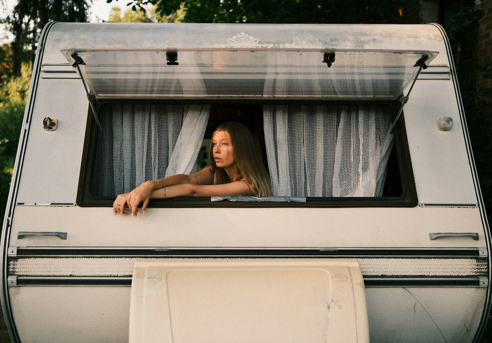 Woman leaning on the open push-out window of a camper